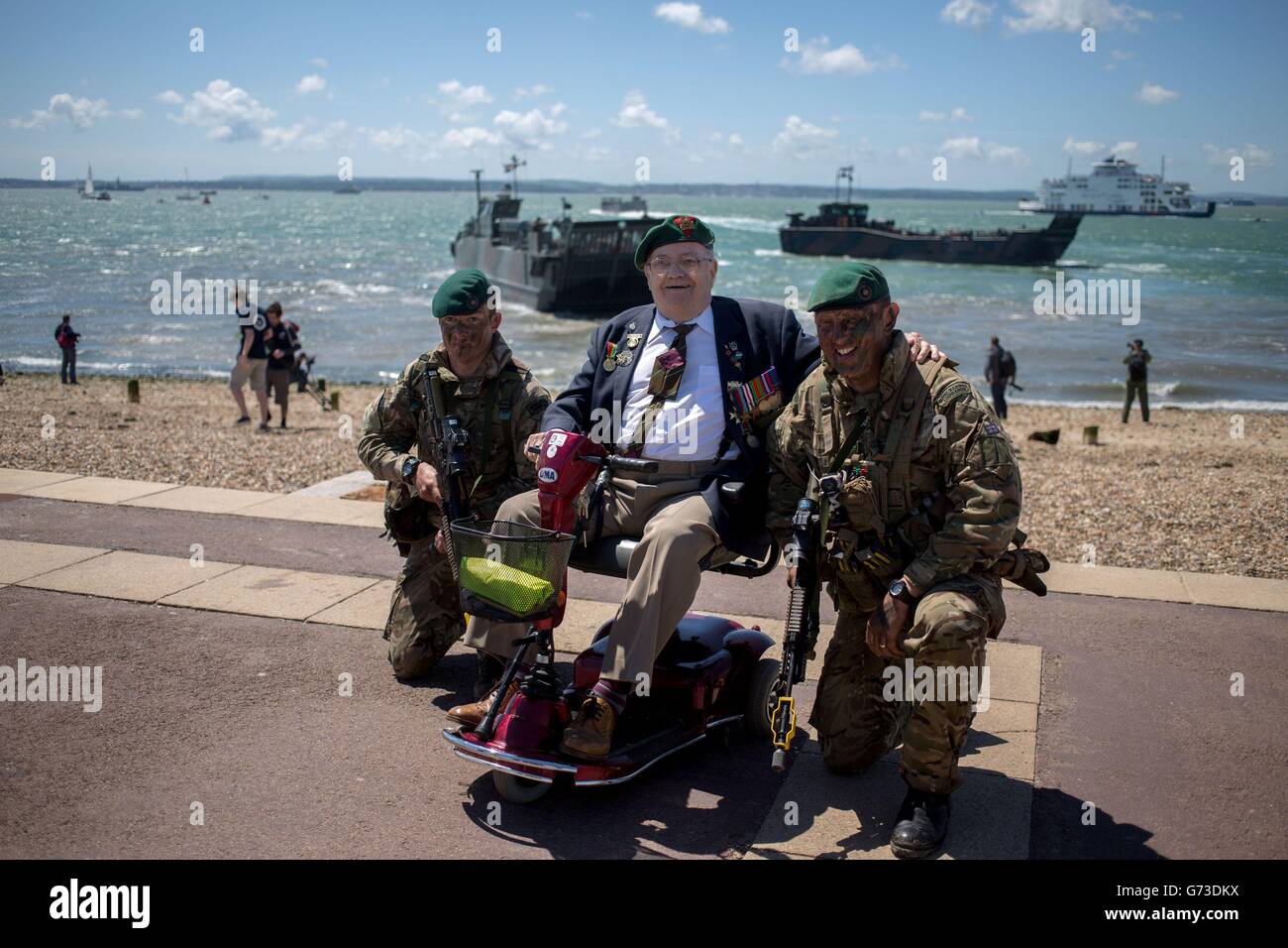 Marine Commandos Tom Meehan (a sinistra) e Jonathan Bowen parlano con Veteran Fred Perkins, 89 anni, dopo che i Marines insieme ai loro omologhi olandesi eseguirono un'invasione di spiaggia vicino Southsea Common in Hampshire per celebrare il 70° anniversario degli sbarchi del D-Day. Foto Stock