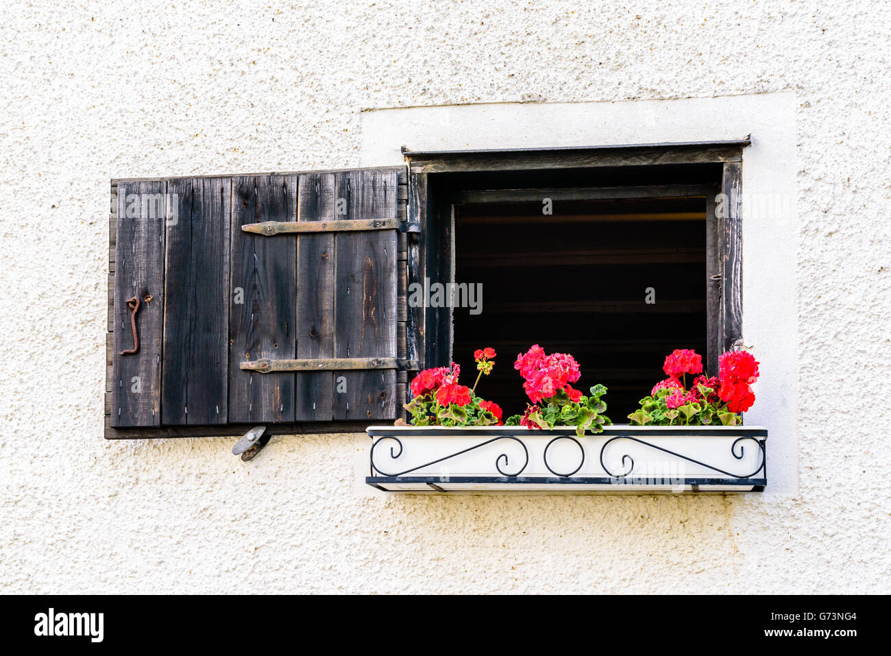 Aprire la finestra o berlina con fiori di colore rosso in una cassetta per  fiori appesi al di fuori. Legno nero otturatore è aperto Foto stock - Alamy