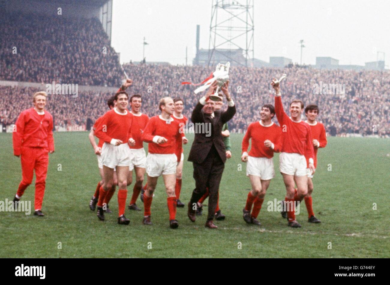 Il manager del Manchester United Matt Busby (quarta r) tiene il trofeo del campionato di campionato aloft mentre lui e i suoi giocatori lo sfilano intorno a Old Trafford: (l-r) Denis Law, Bill Foulkes, Shay Brennan, David Sadler, Bobby Charlton, Jimmy Ryan, Busby, Alex Stepney, Tony Dunne, Pat Crerand, George Best Foto Stock