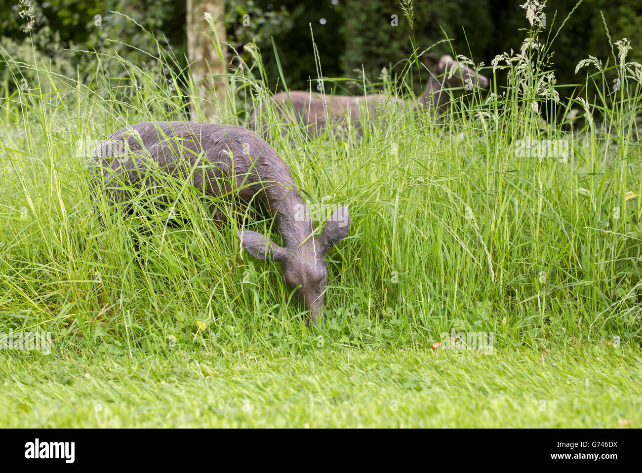Deer scultura in erba lunga in un giardino di Cotswold. Cotswolds, Inghilterra Foto Stock