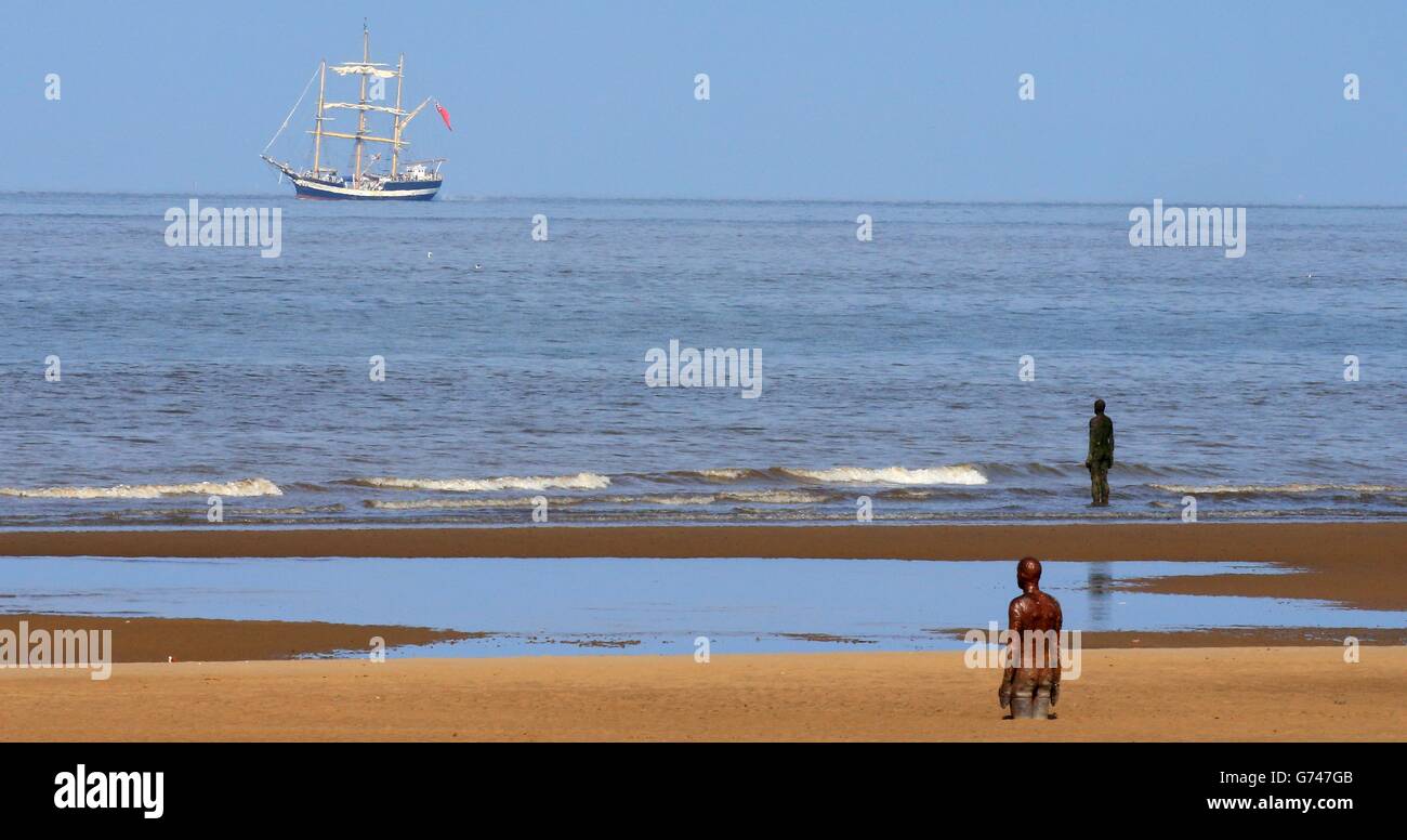 Una vista generale della scultura di Antony Gormley's Another Place su Crosby Beach mentre la nave alta Pelican of London passa davanti al windfarm appena fuori dalla spiaggia di Crosby, Merseyside, la barca fa parte del Mersey River Festival che si svolge questo fine settimana a Liverpool. Foto Stock