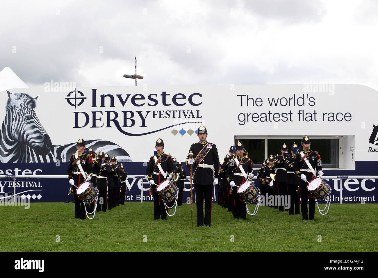 Una banda militare marcia lungo la pista durante Investec Derby Giorno 2014 all'Ippodromo di Epsom Downs Foto Stock