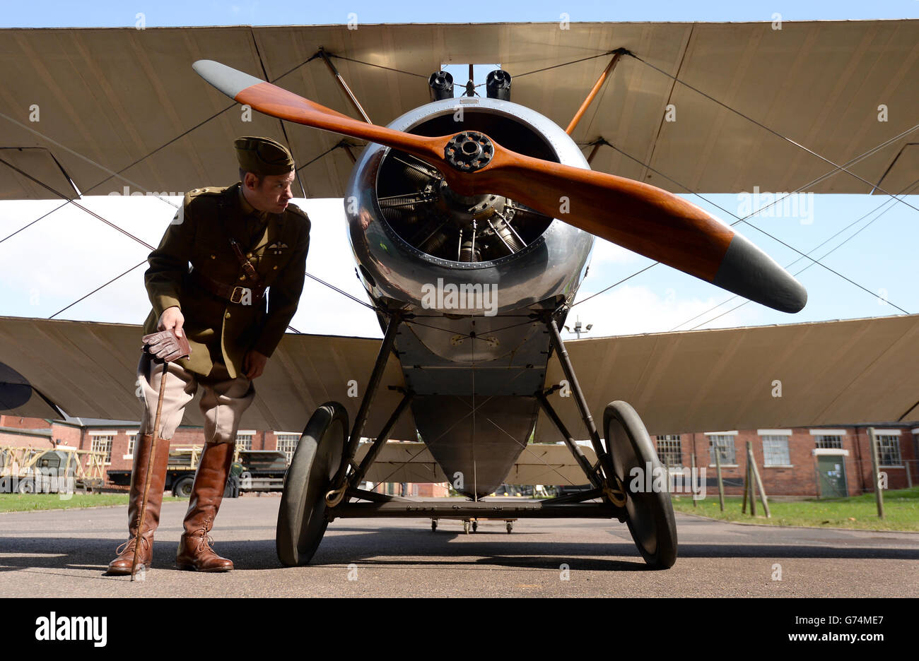 Un re-enattore storico nell'abbigliamento vintage dell'ufficiale della prima Guerra Mondiale si pone di fronte a un biplano Sopwith Camel prima di entrare nel nuovo spazio espositivo dedicato a raccontare la storia della prima guerra mondiale in aria al RAF Musuem, Londra. Foto Stock