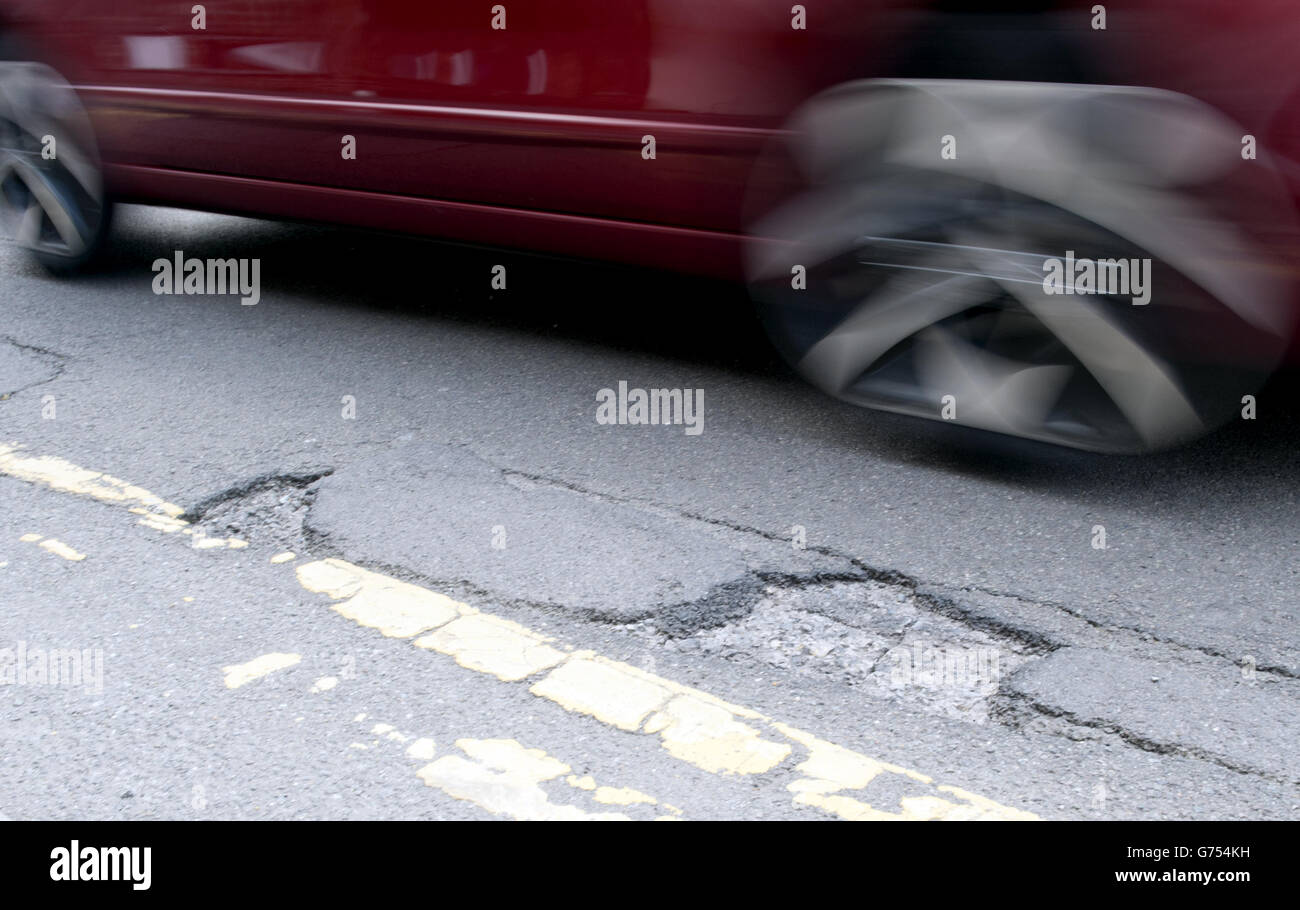 Stock di potole. Un'auto guida su una buche su una strada a Kimberley, Nottingham Foto Stock