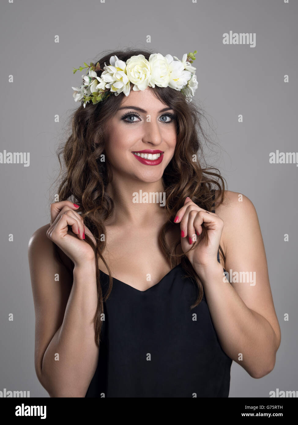 Bellissima ragazza con i fiori nei capelli in posa nella camicia nera  guardando la fotocamera su grigio di sfondo per studio Foto stock - Alamy
