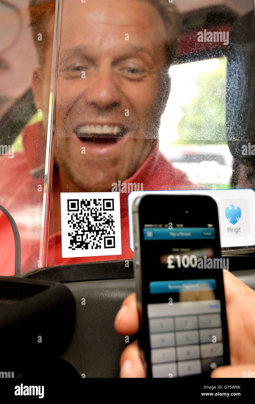 Il driver dei taxi di Londra nera Ian Cable guarda come un passeggero paga per la sua corsa, all'interno del suo taxi senza contanti in Smithfields Market, nel centro di Londra, prima di fare la prova della nuova app Barclays Bank PingIt, ciò consente ai passeggeri di pagare il viaggio semplicemente scansionando il codice a barre quadrato a lettura rapida sul proprio telefono cellulare. Foto Stock