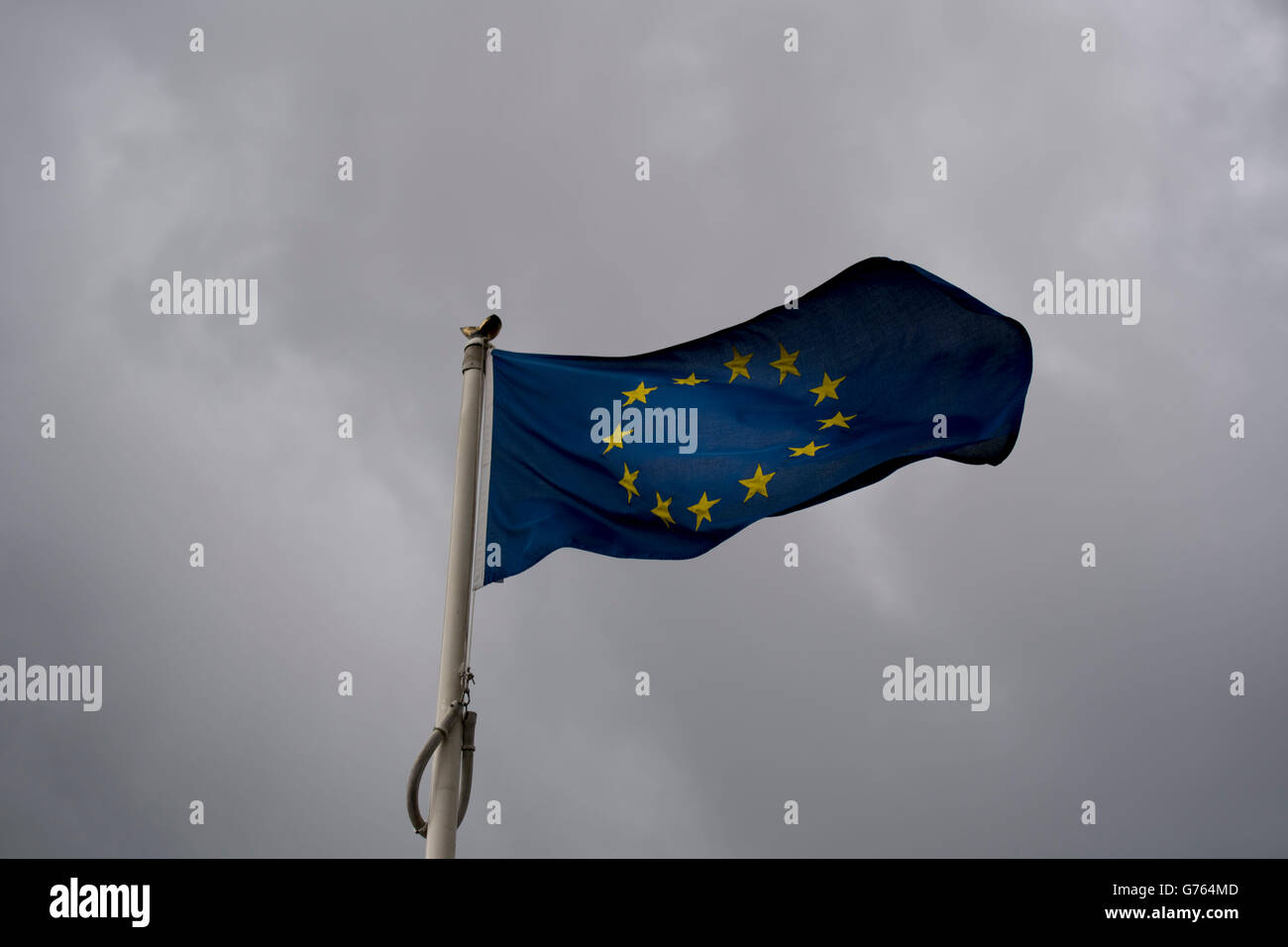 Unione Europea (UE) bandiera al vento con Dark nuvole temporalesche dietro. La Gran Bretagna ha lasciato il UE in un recente referendum. Foto Stock