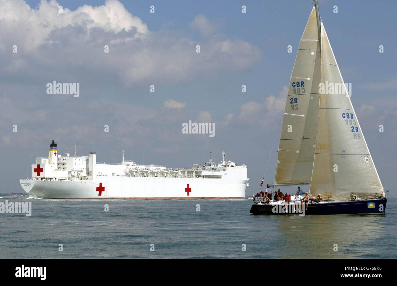 La nave Comfort dell'ospedale navale degli Stati Uniti parte dal Solent Off Cowes, Isola di Wight, passando davanti a yacht che gareggiano il terzo giorno della regata velica della Cowes Week. Le corse sono state abbandonate tranne che per quattro classi a causa della mancanza di vento. *... lasciando la maggior parte delle 890 barche e 8,000 marinai becalmed. Foto Stock