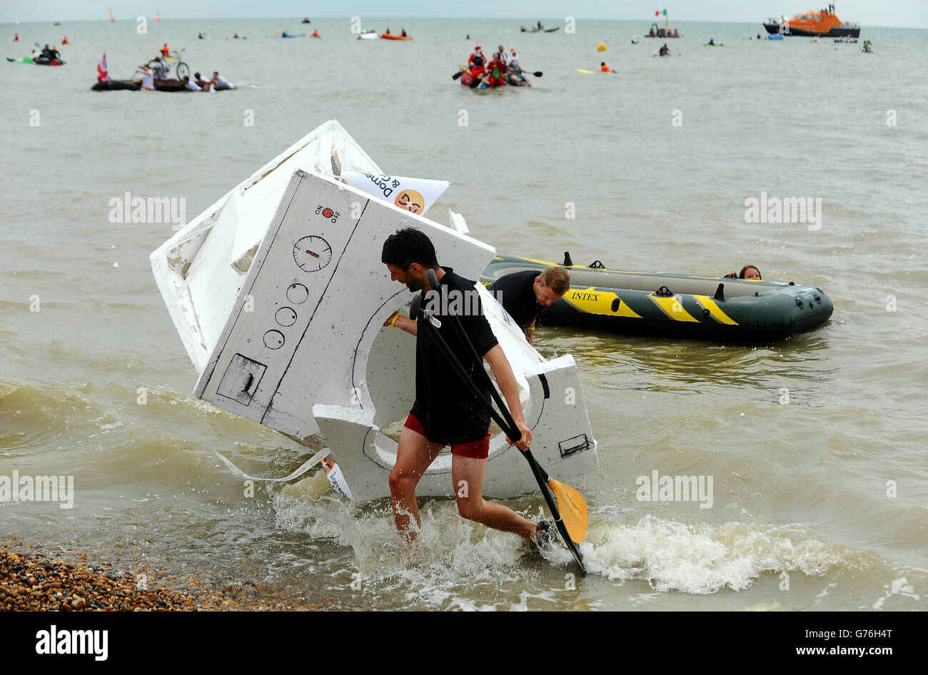 I concorrenti portano pezzi della loro zattera dopo aver partecipato all'evento "Paddle Something insolite" al Paddle Round The Pier Beach Festival di Brighton. Foto Stock