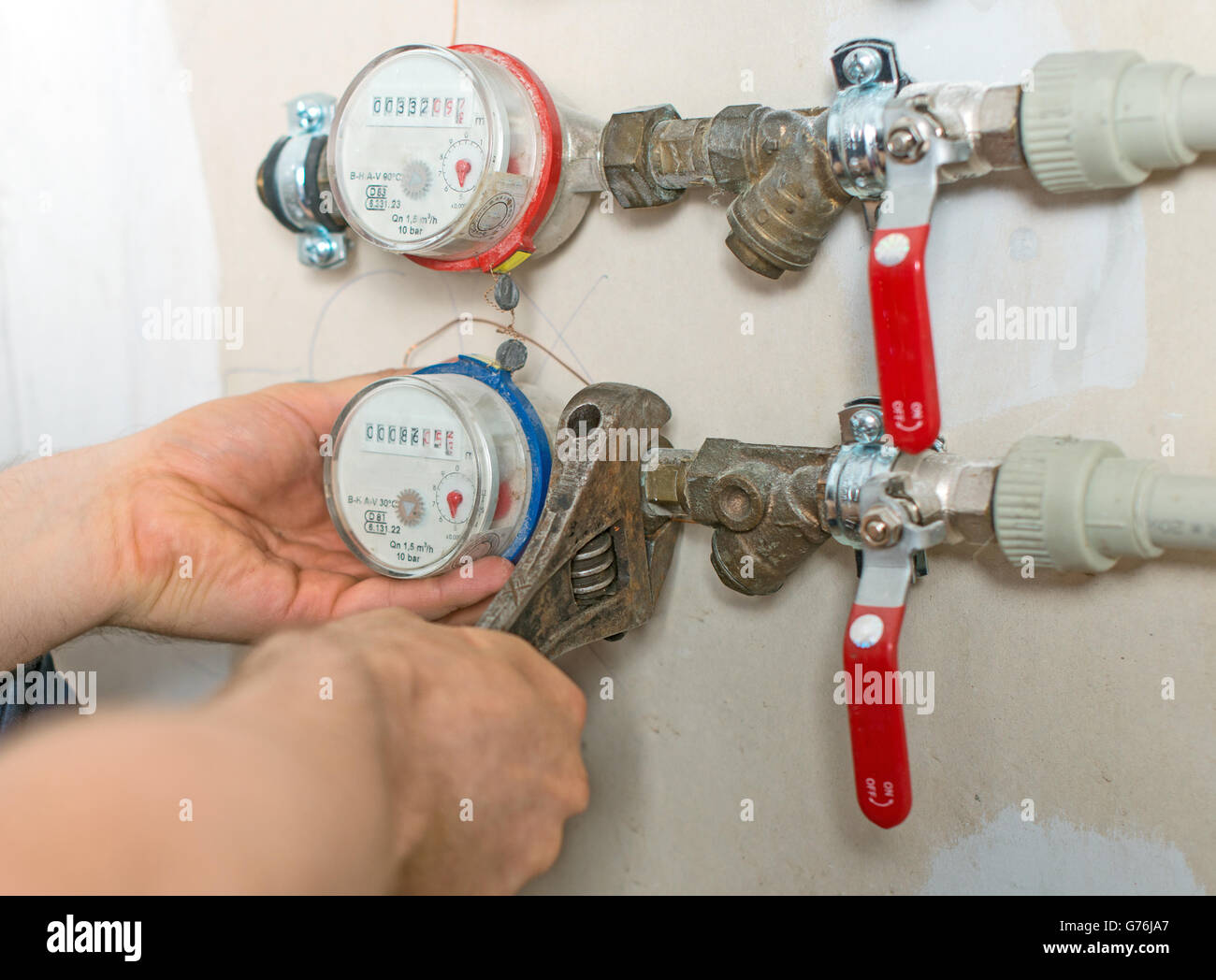 Idraulico maschio che fissa misuratore di acqua con una chiave regolabile. Foto Stock