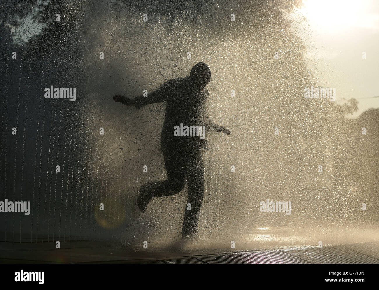 Un uomo completamente vestito esce dalla fontana d'acqua di Jeppe Hein's apparendo Rooms sulla Southbank, a Londra. Foto Stock