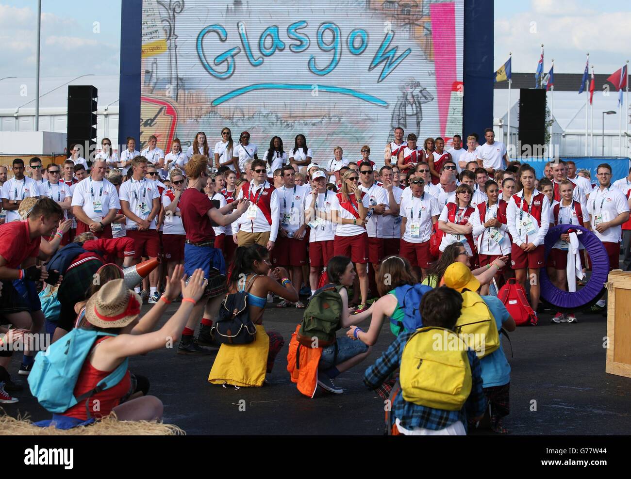 Atleti e funzionari guardano una performance durante la cerimonia di benvenuto del Team England al Villaggio degli atleti di Glasgow. Foto Stock