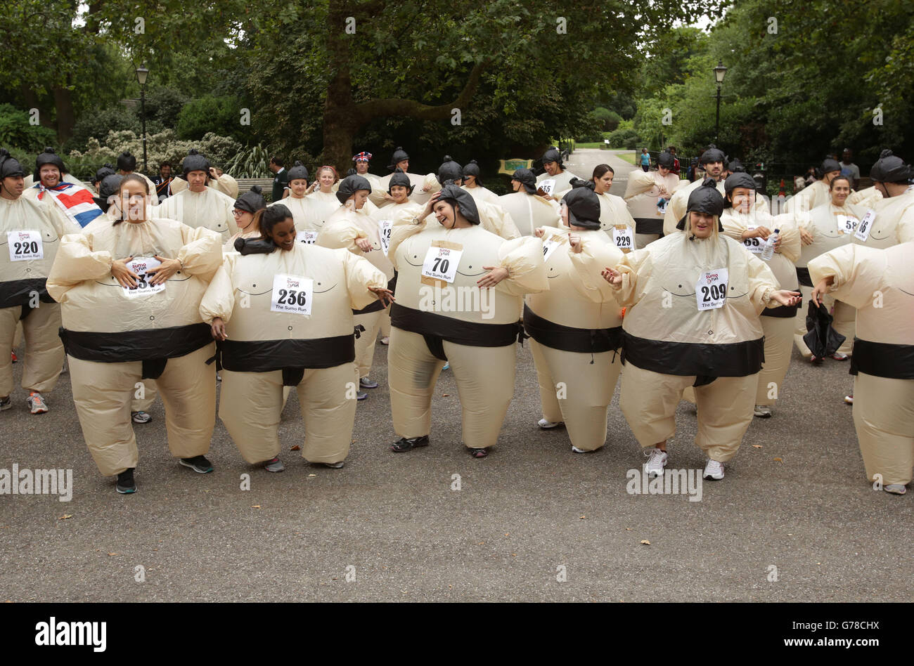I partecipanti si riscaldano prima di partecipare al Sumo Run, una divertente corsa di beneficenza da 5 km per i corridori che indossano abiti da sumo gonfiabili, a Battersea Park, Londra. Foto Stock