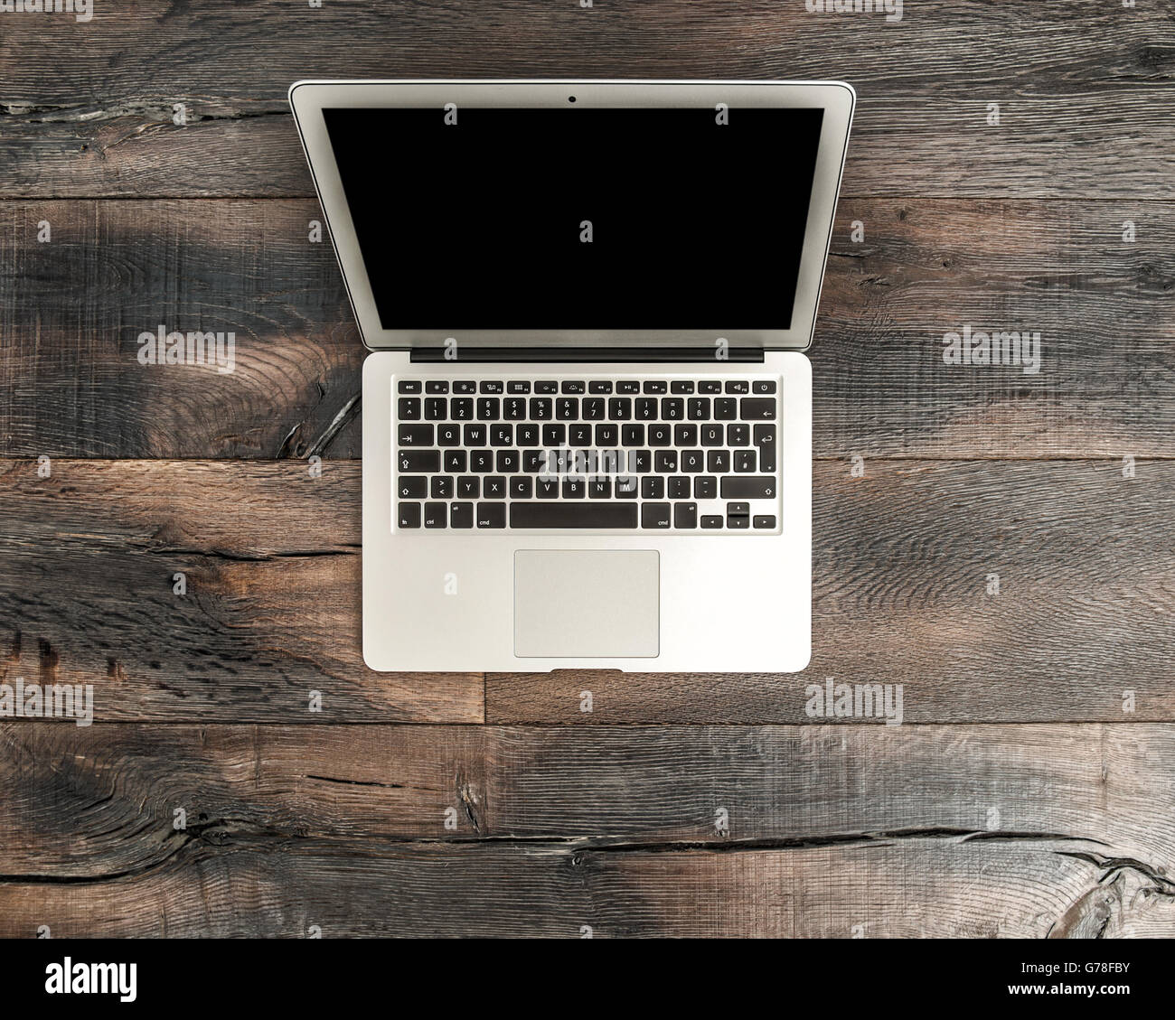 Laptop notebook con schermo nero su un tavolo di legno scrivania. Area di lavoro di Office background. Scritte in tedesco Foto Stock
