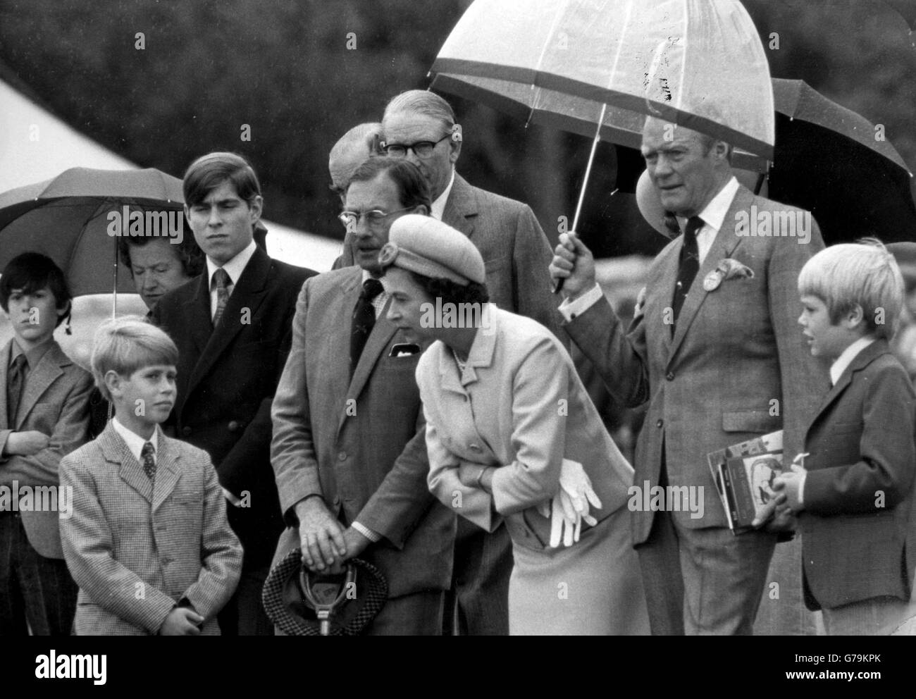 La regina si inclina a parlare con il principe Edoardo, mentre è al riparo dalla pioggia dal duca di Wellington. Stavano partecipando all'annuale Game Fair nei terreni di Stratfield Saye. Dietro Edoardo si trova il principe Andrew, mentre il figlio più giovane del duca, Lord Christopher Wellesley, è sulla destra. Foto Stock