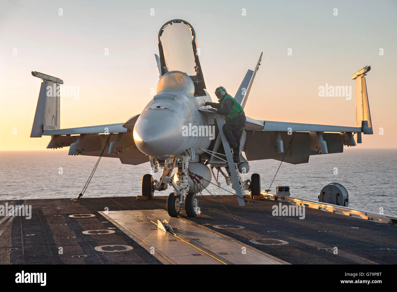 Un US Navy Aviation Electronics il tecnico esegue la manutenzione di un F/A-18E Super Hornet aerei sul ponte di volo della portaerei USS Dwight D. Eisenhower al tramonto Giugno 14, 2016 nel mar Mediterraneo. Foto Stock