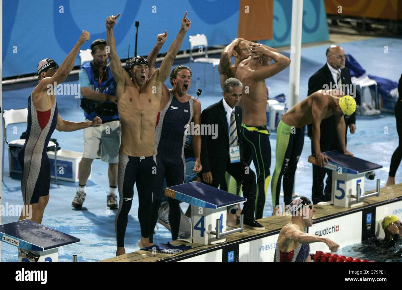 Da sinistra, i membri del team di relè americani Peter Vanderkaay, Micheal Phelps, Ryan Lochte e Klete Keller (in piscina) festeggiano dopo aver vinto la staffetta Freestyle da 4 x 200 m per uomini al Centro Acquatico Olimpico di Atene, Grecia. Nella foto sono anche i membri del team australiano (a destra) che hanno finito secondo. Foto Stock