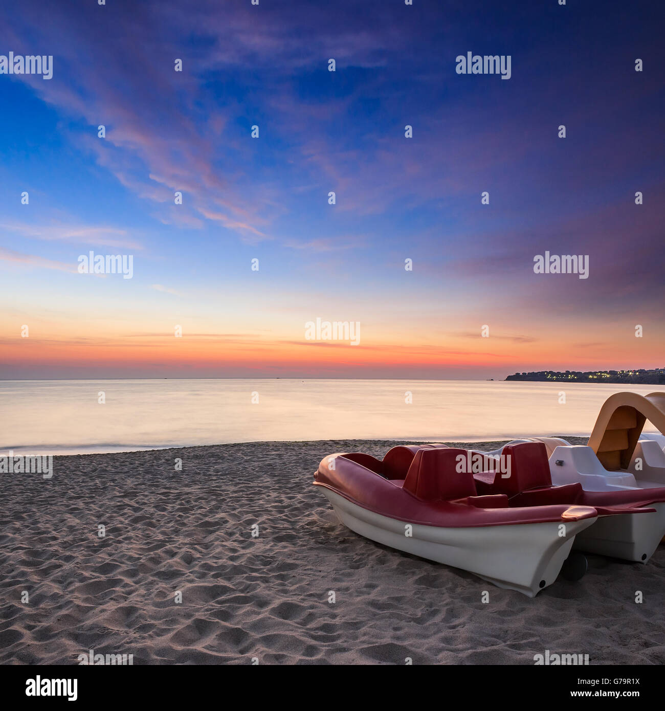 Mare calmo onde toccare spiaggia sabbiosa con poche barche all'alba Foto Stock