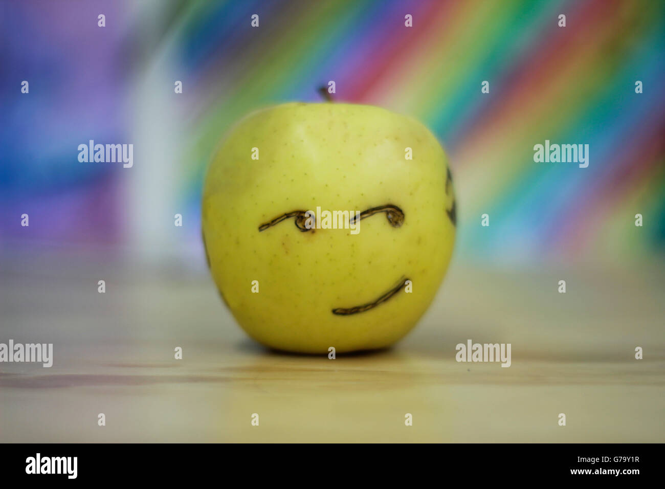 Photograh di un Apple con una felice volto sorridente e colorato sfondo sfocato Foto Stock