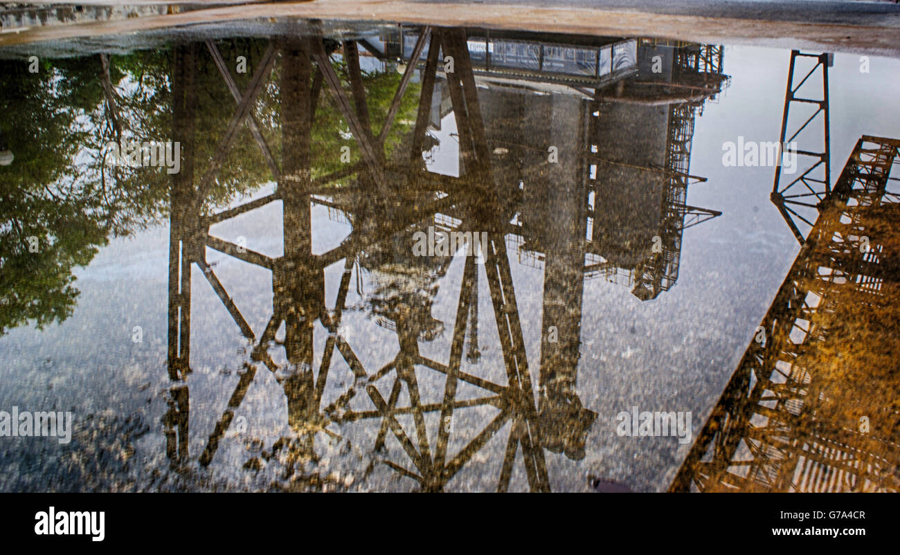 Fotografia di una struttura industriale riflettendo su una pozzanghera Foto Stock