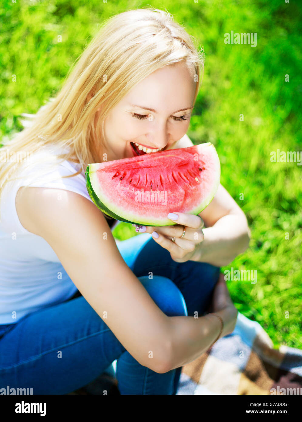 Felice giovane donna bionda di mangiare un cocomero in estate park Foto Stock