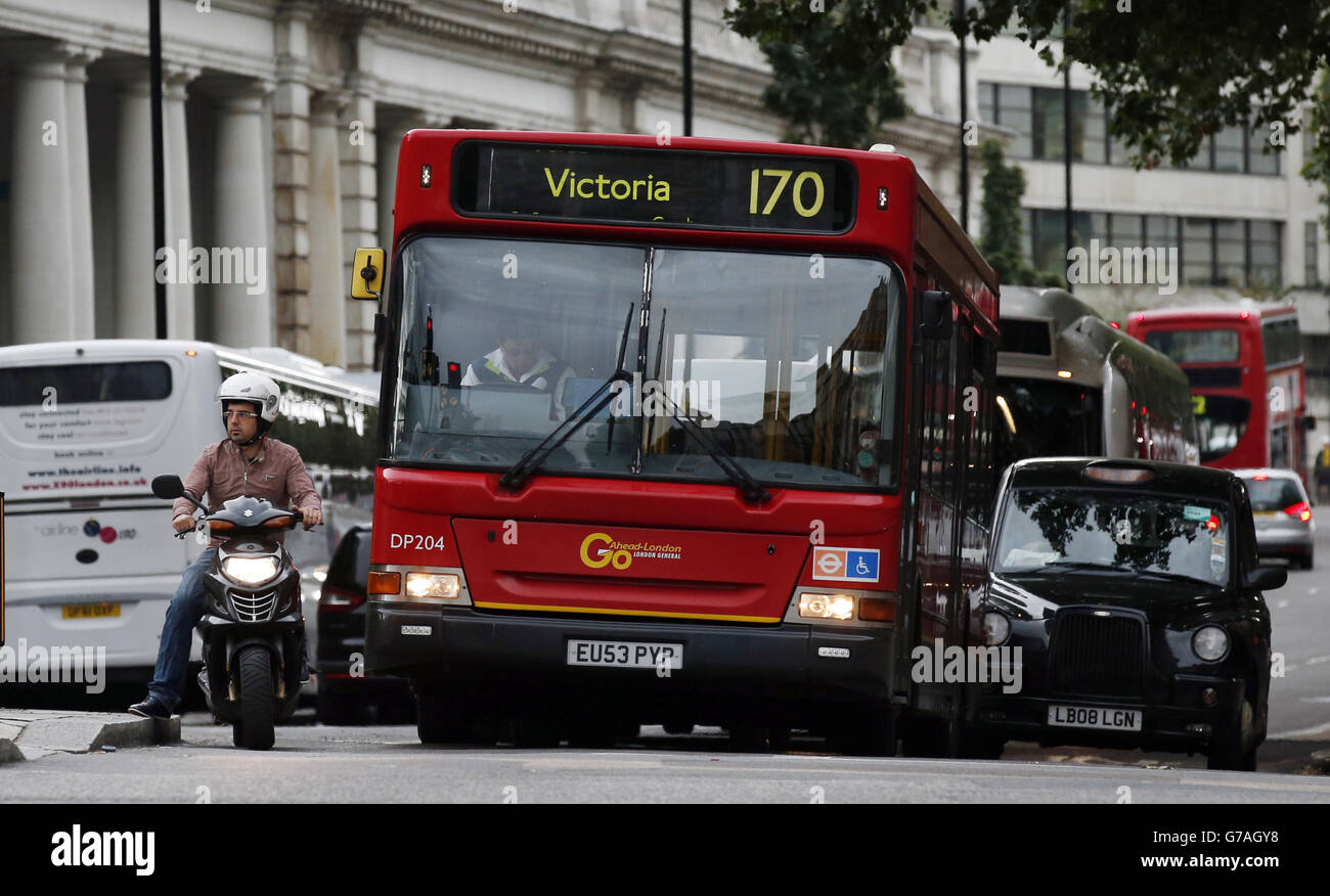 Stock di traffico. Al semaforo di Buckingham Palace Road, Westminster, Londra, si trova un ciclomotore, un autobus e un taxi. Foto Stock