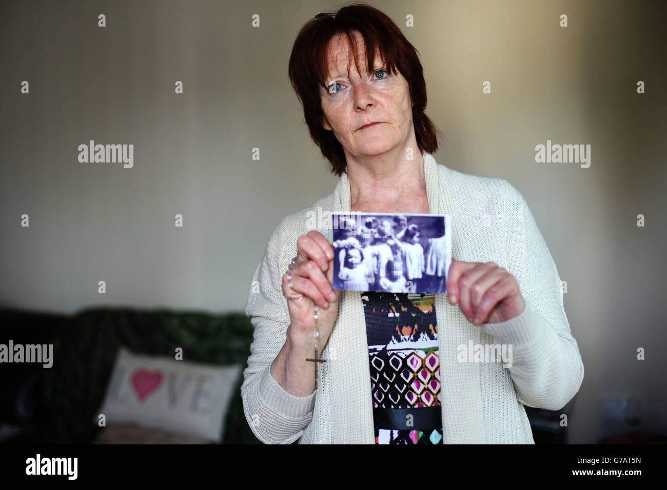 RICHIESTA di abuso DI NI. Il superstite Kate Walmsley, nella sua casa a Belfast, ha tenuto una foto che mostra i bambini in una casa residenziale a Londonderry con Kate (davanti a sinistra) e Margaret McGuckian, fondatore dei Survivor e delle vittime di abusi istituzionali (seconda a destra). Foto Stock