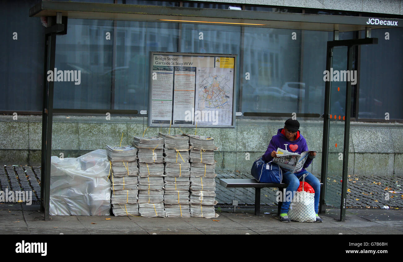 Una signora legge una copia del giornale di Manchester Evening News mentre attende un autobus a Manchester. Foto Stock