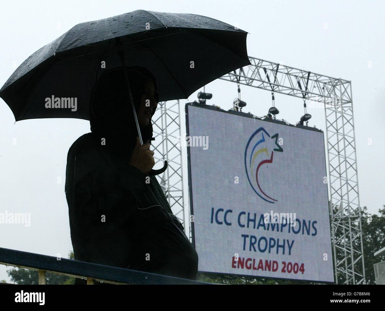 NESSUN UTILIZZO DEL TELEFONO CELLULARE. Un fan di cricket si rifugia sotto un ombrello mentre la pioggia smette di giocare a Edgbaston, Birmingham, con l'Inghilterra a causa di giocare Zimbabwe durante la prima partita del Trofeo ICC Champions, One Day International. Foto Stock