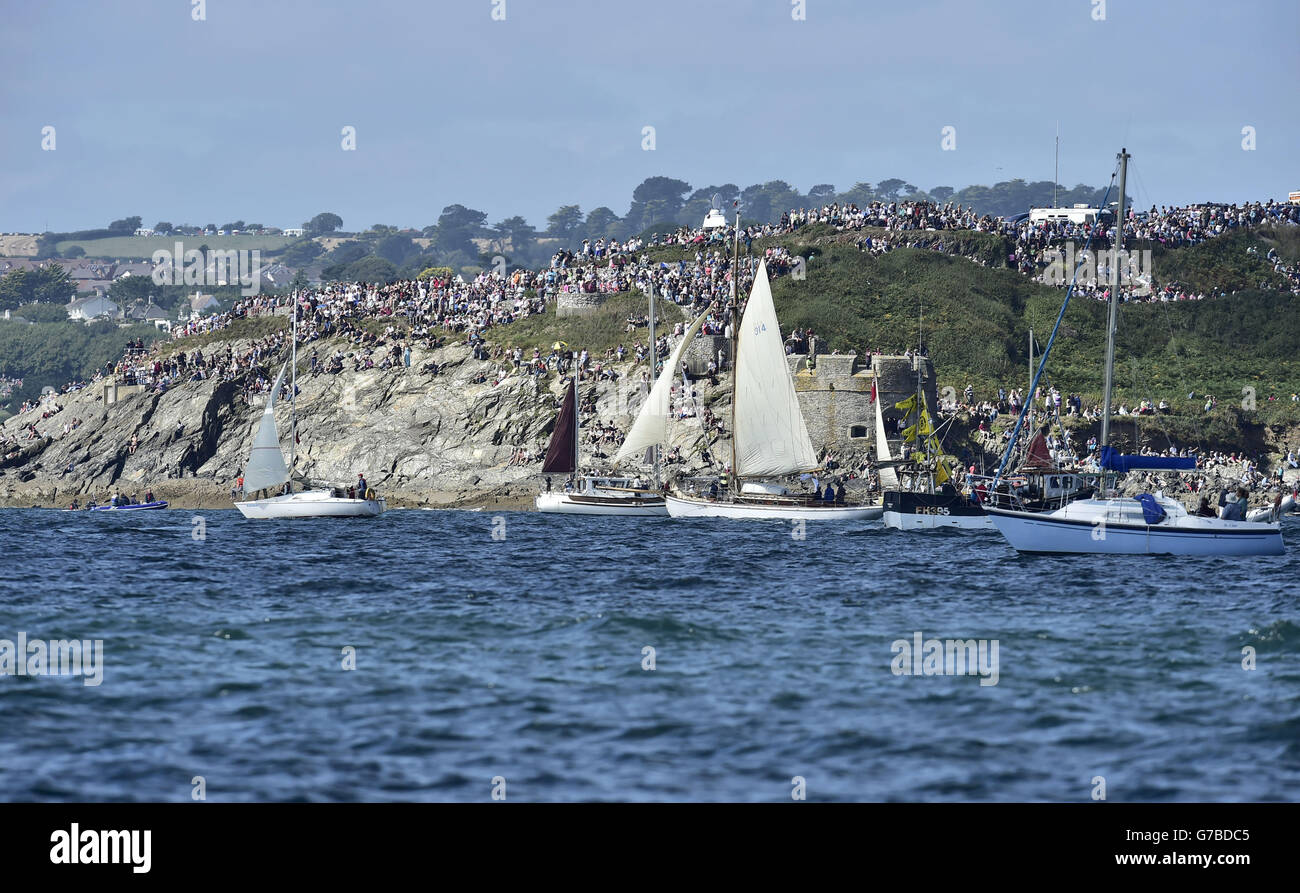 Folle di spettatori si riuniscono per guardare alte navi che prendono parte alla Parata di vela dal porto di Falmouth mentre si dirigono verso il punto di partenza per la corsa a Greenwich, Londra, sotto la vela. Foto Stock