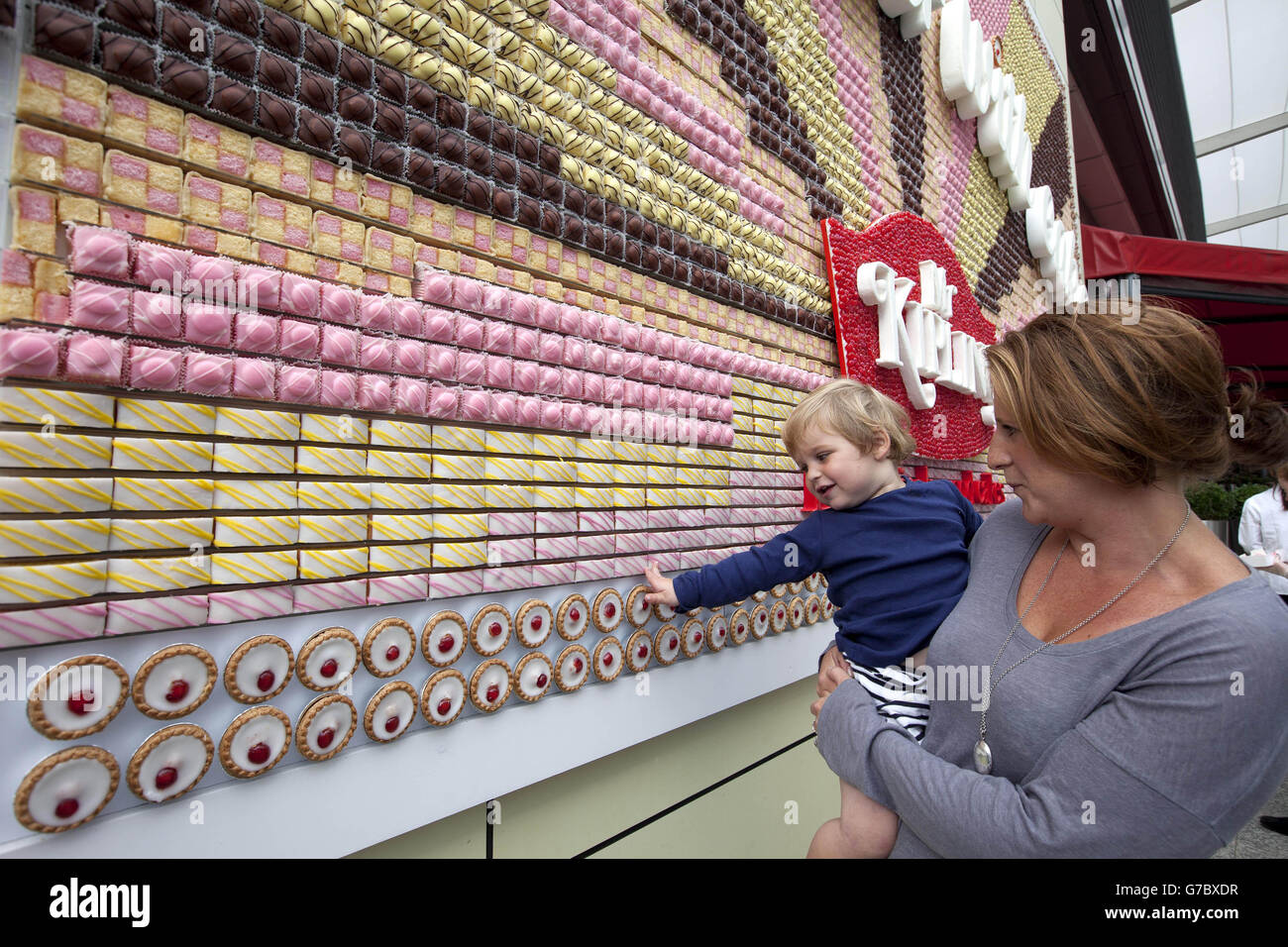 Gemma Goodfellow e suo figlio Sam, 1, guardano un manifesto commestibile fatto da oltre 13,000 MR Kipling Cakes - che scrive 'la vita è migliore con torta', che è stato installato al Westfield London Shopping Centre a Shepherds Bush. Foto Stock