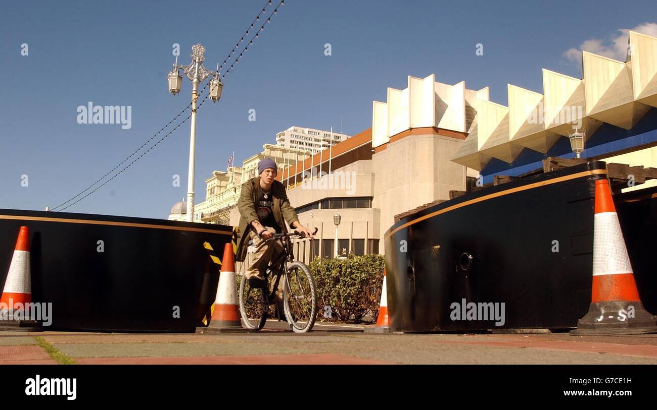 Un uomo in bicicletta, attraversa enormi barricate in cemento e acciaio erette lungo il lungomare di Brighton, di fronte al Brighton Conference Center. Gli enormi ostacoli fanno parte dell'"anello d' acciaio", intorno alla sede della Conferenza del Partito laburista, che inizia domenica prossima. Foto Stock