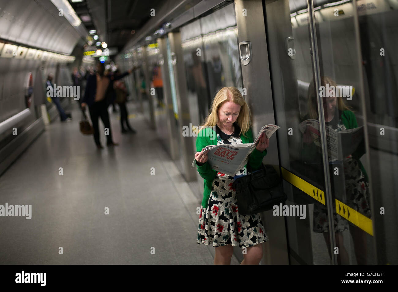 Un pendolarista legge un giornale mentre attende un treno Jubilee Line alla stazione della metropolitana di Westminster nel centro di Londra. Foto Stock