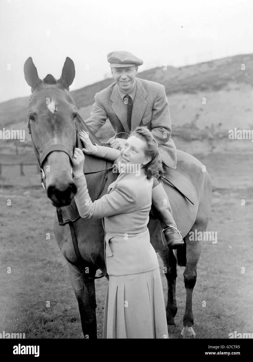 George Formby, scenografo del Lancashire e comico dello schermo, in una visita alla sua contea di casa per un aspetto personale, ha preso il tempo di indulgere nel suo passatempo preferito, l'equitazione. Qui si trova in Irlanda con sua moglie Beryl quando visitarono la School of Equitation vicino a Prestwich, Lancashire. Foto Stock