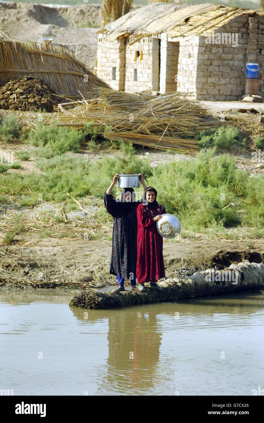 Due donne locali della tribù araba marsh raccolgono l'acqua come un plotone dal Black Watch Visita la zona, come parte di una campagna di cuori e menti nella provincia di Maysan, Iraq del Nord. Foto Stock