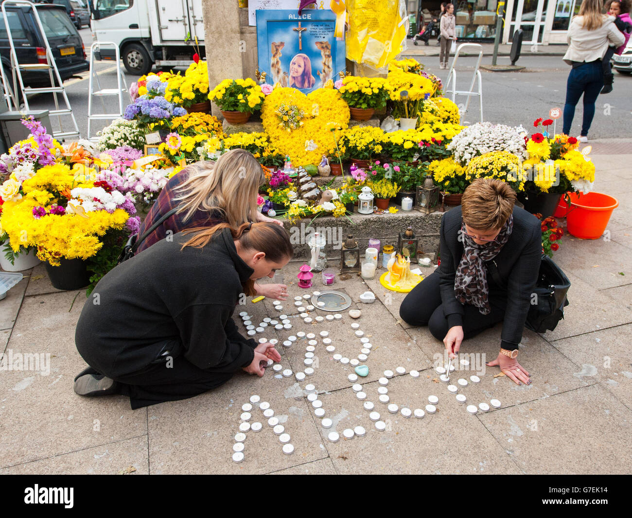 I Mourners illuminano le candele in memoria dell'adolescente assassinato Alice Gross alla Torre dell'Orologio di Hanwell mentre il traffico si fermò e i locali uscirono a pagare i loro omaggi ad Hanwell, Londra occidentale, mentre il suo corteo funebre passò attraverso con una scorta di polizia. Foto Stock