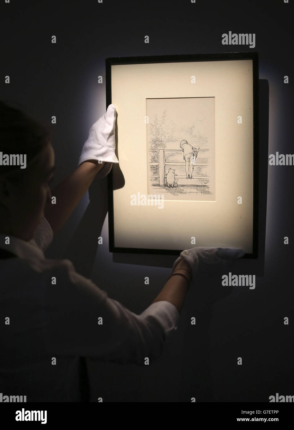 Il tecnico della galleria di Sotheby appende un disegno alla casa d'aste nel centro di Londra da E.H Shepard di Winnie the Pooh, come l'orso suona 'Poohsticks' con Piglet e Christopher Robin, una delle immagini più famose, che si prevede di recuperare più di &Pound;100,000 all'asta. Foto Stock