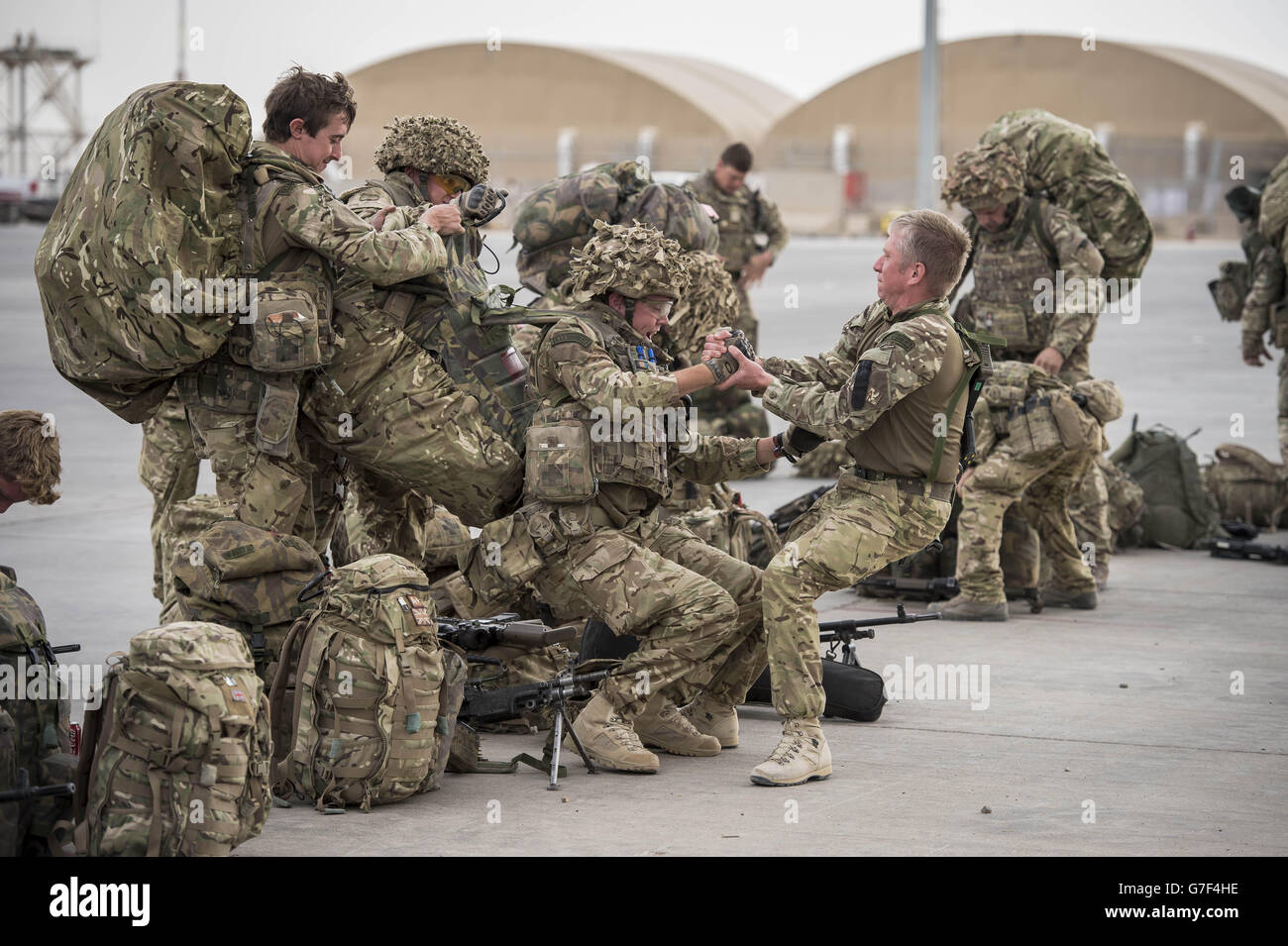 Le truppe si aiutano a vicenda con pesanti zaini Bergen e sistemi di armi mentre alcune delle ultime truppe britanniche si preparano a lasciare il Bastione del campo, la provincia di Helmand, l'Afghanistan, mentre le forze britanniche e della Coalizione effettuano il loro ritiro tattico lasciando finalmente la base e consegnandola all'esercito nazionale afgano. Foto Stock