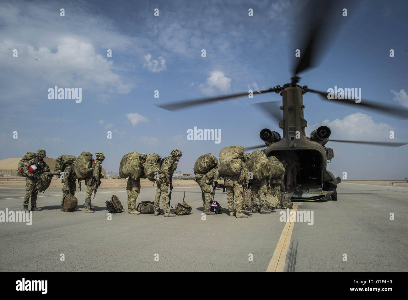 Il comandante dell'ala Matt Radnall, ufficiale che comanda l'ala di protezione della forza 7, raffigurato a sinistra, porta una bandiera dell'Unione piegata con cura sotto il braccio e torna a casa nel Regno Unito mentre si prepara a salire a bordo dell'ultimo elicottero Chinook come l'ultimo stivale britannico a lasciare Camp Bastion, Helmand Province, Afghanistan, Mentre il Regno Unito e le forze della Coalizione effettuano il loro ritiro tattico finalmente lasciando la base e consegnandola all'esercito nazionale afgano. Foto Stock