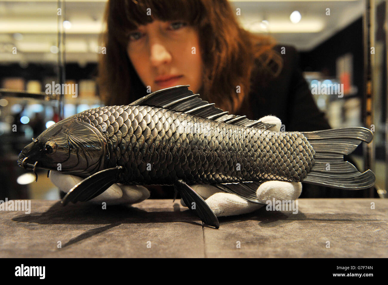 Danielle DeMartini, membro dello staff di Bonhams, detiene una carpa articolata in argento puro di Takase Torakichi, conosciuta come Kozan, stimata a £60,000 - £80,000, durante un'anteprima per il prossimo fine Japanese Art sale di Bonhams nel centro di Londra. Foto Stock
