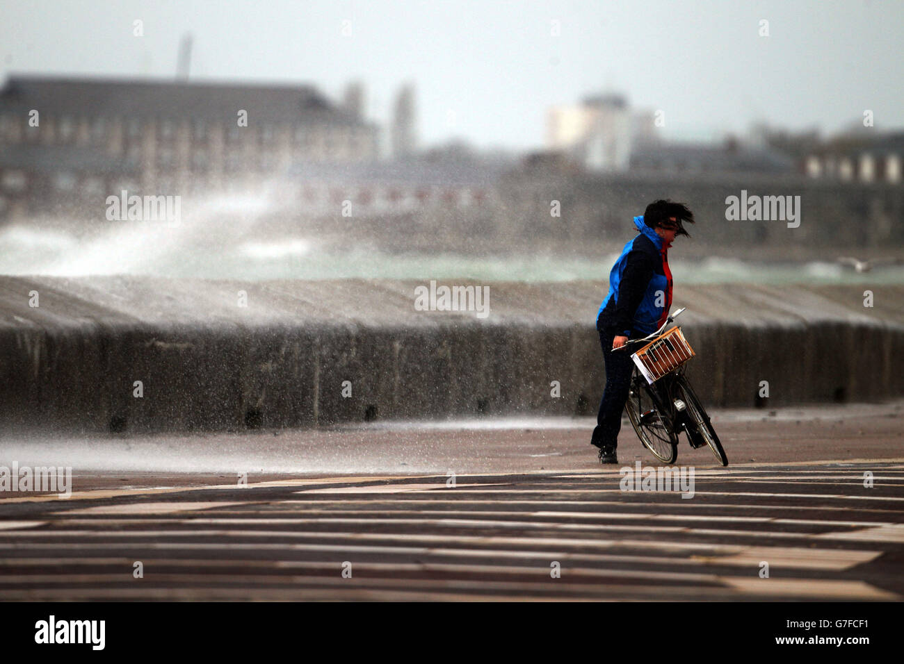Un ciclista bravica il forte vento sul lungomare di Southsea, vicino a Portsmouth, Hampshire. Foto Stock
