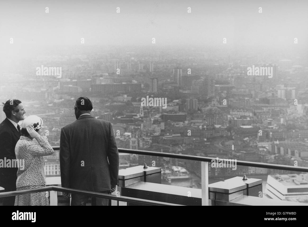La regina Elisabetta II tiene il cappello durante un tour del tetto sulla National Westminster Tower. Mostrando il suo intorno al blocco torre su Old Broad Street sono stati Robin Leigh-Pemberton (a sinistra), presidente della NatWest Bank, e FG (Jack) Bennie, direttore della divisione premises. Foto Stock
