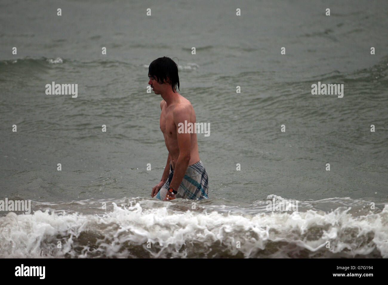 Un nuotatore breccia l'acqua mentre il vento forte e la pioggia e le maree colpiscono il lungomare di Southsea, vicino a Portsmouth, Hampshire. Foto Stock