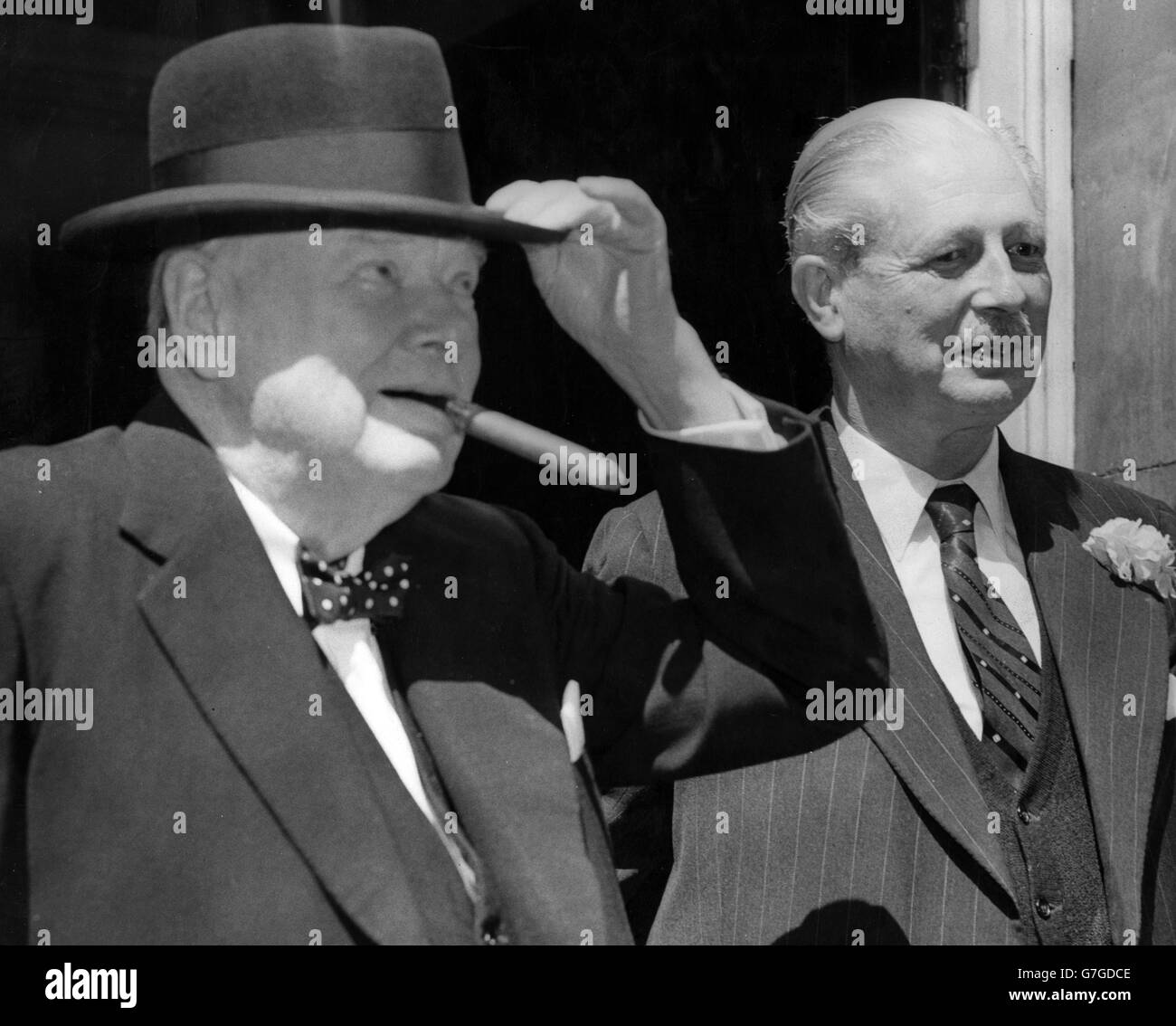 Sir Winston Churchill gode di un sigaro dopo pranzo mentre lascia Downing Street nel 10 con il primo ministro Harold Macmillan. Foto Stock