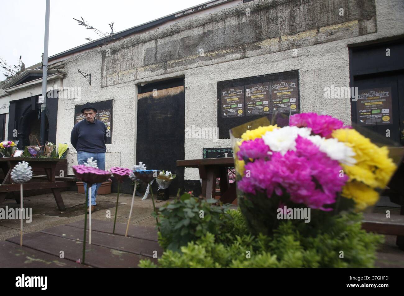 Un uomo guarda agli omaggi floreali di fronte al pub Clutha a Glasgow, Scozia, come un servizio si svolge nella Cattedrale di Glasgow in occasione del primo anniversario del crash elicottero che ha causato la morte di dieci persone. Foto Stock