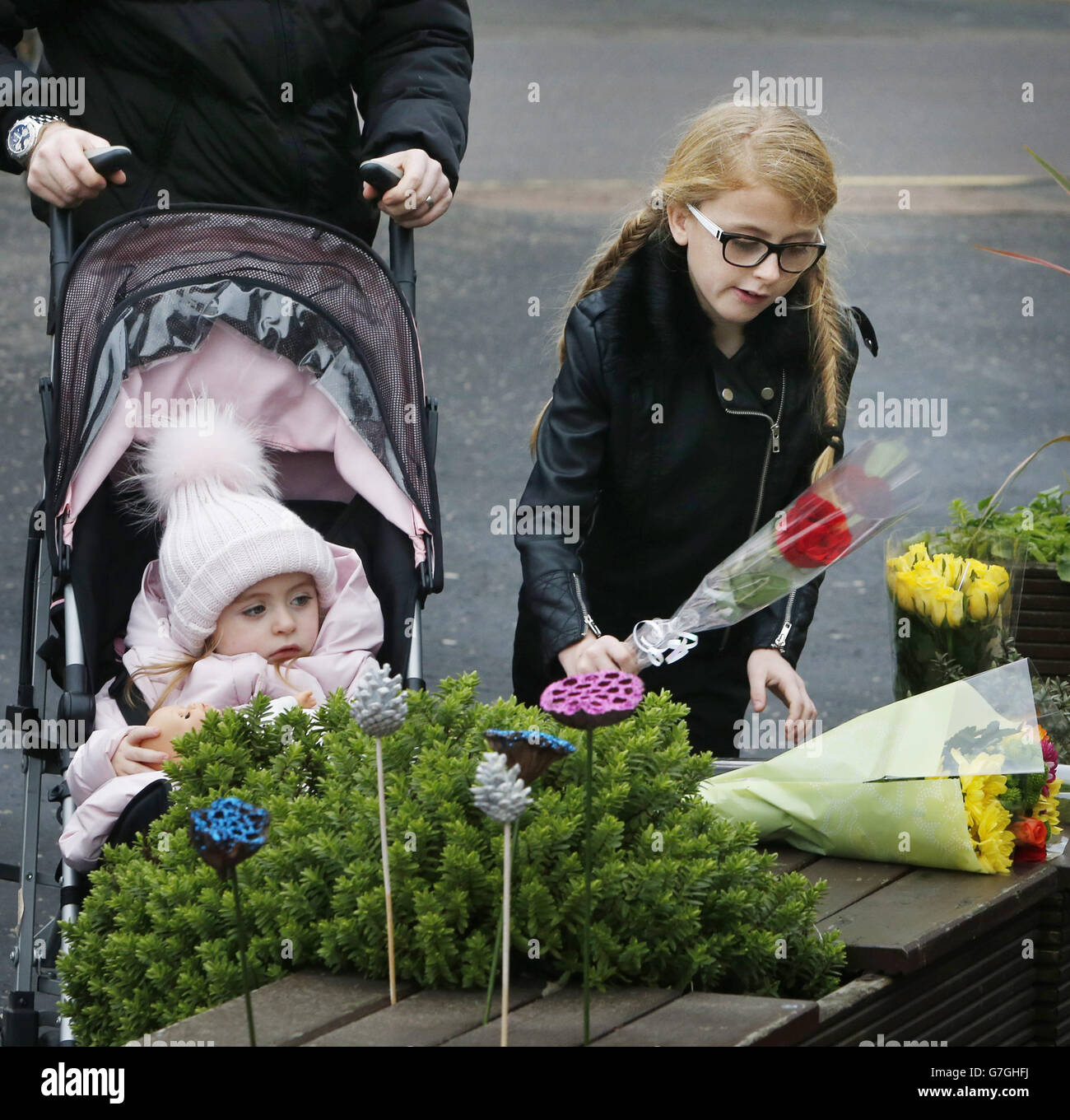 Un bambino depone fiori al pub di Cutha a Glasgow, Scozia, come un servizio si svolge nella Cattedrale di Glasgow, in occasione del primo anniversario del crash elicottero che ha causato la morte di dieci persone. Foto Stock