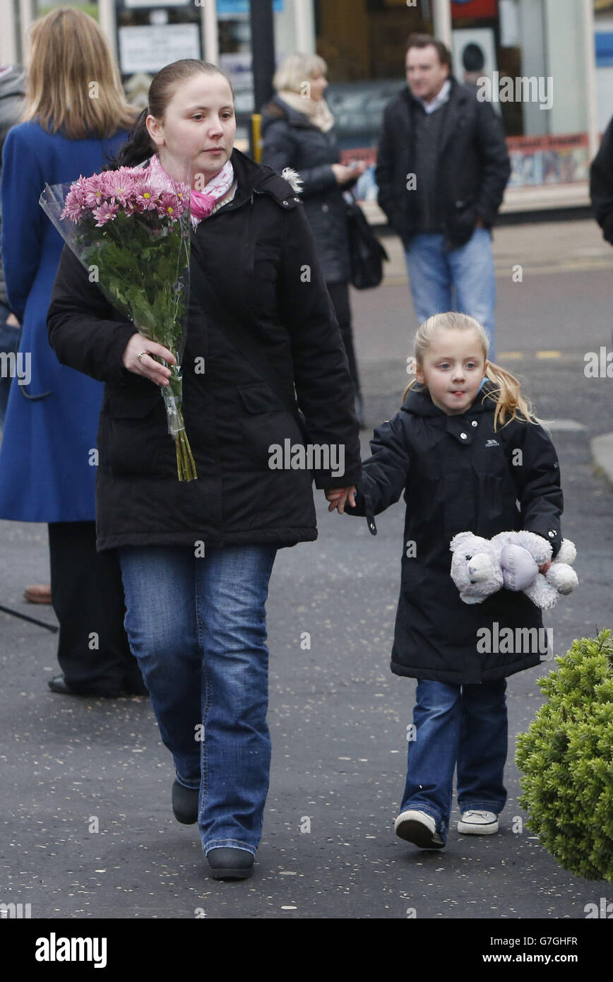 Una donna porta fiori a posare al pub di Clusha a Glasgow, Scozia, come un servizio si svolge nella Cattedrale di Glasgow, in occasione del primo anniversario del crash elicottero che ha causato la morte di dieci persone. Foto Stock