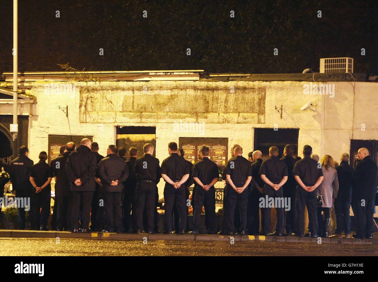 I membri dei servizi di emergenza e il pubblico si riuniscono davanti a un minuto di silenzio alle 22:22 fuori dalla Clutha a Glasgow, in Scozia, per segnare il momento in cui un elicottero di polizia si è schiantato causando la morte di dieci persone un anno fa. Foto Stock