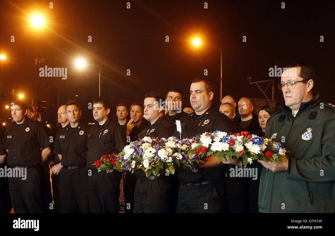 I membri dei servizi di emergenza hanno tributi floreali davanti a un minuto di silenzio alle 22:22 fuori dalla Clutha a Glasgow, in Scozia, per segnare il momento in cui un elicottero di polizia si è schiantato causando la morte di dieci persone un anno fa. Foto Stock