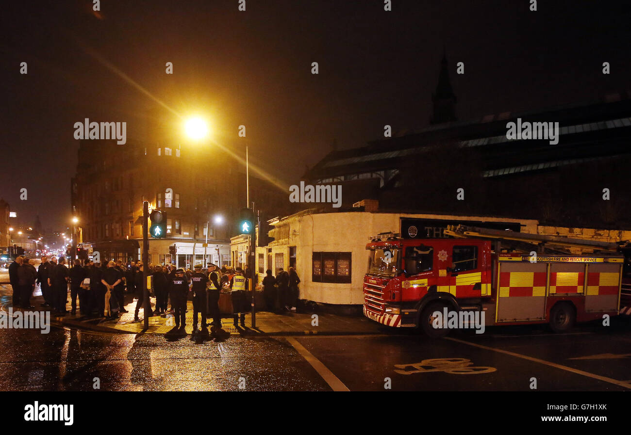 I membri dei servizi di emergenza e il pubblico si riuniscono dopo aver tenuto un minuto di silenzio alle 22:22 fuori del Clutha a Glasgow, Scozia, segnando il momento in cui un elicottero della polizia si è schiantato causando la morte di dieci persone un anno fa. Foto Stock